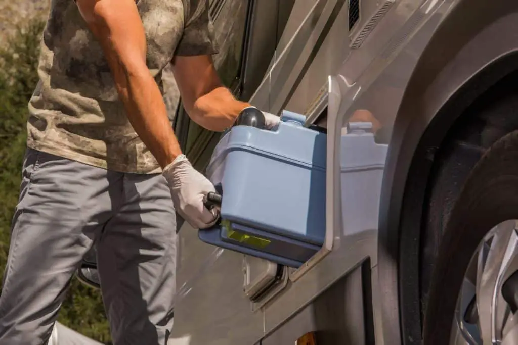 can you put a regular toilet in your RV? photo depicts a man pulling a cassette toilet tank out of his RV camper